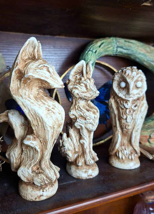A group of handmade ancient-style resin idols designed as archaeological relics displayed on a dark wooden shelf for cabinet of curiosities decor.